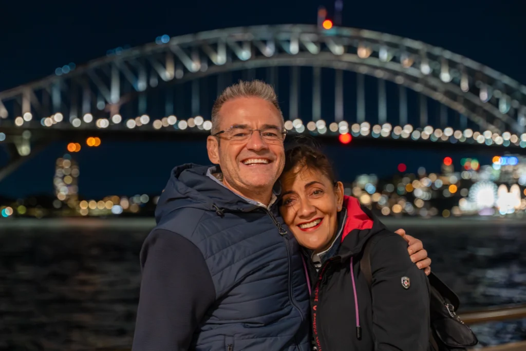 Viajeros frente al Sydney Harbour Bridge durante la noche